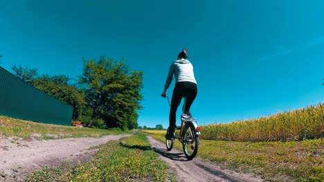 young woman riding vintage bicycle along a rural road in a village