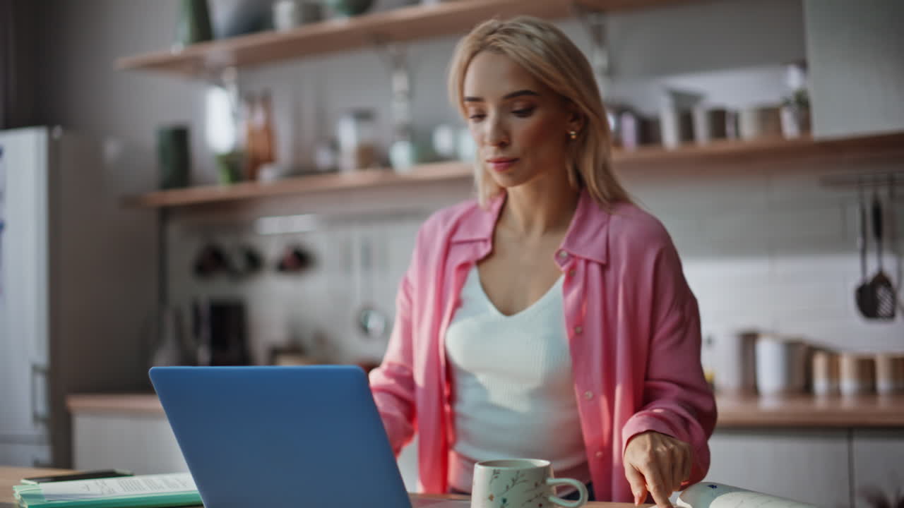 Remote businessw0man browsing computer checking notes at cozy kitchen closeup