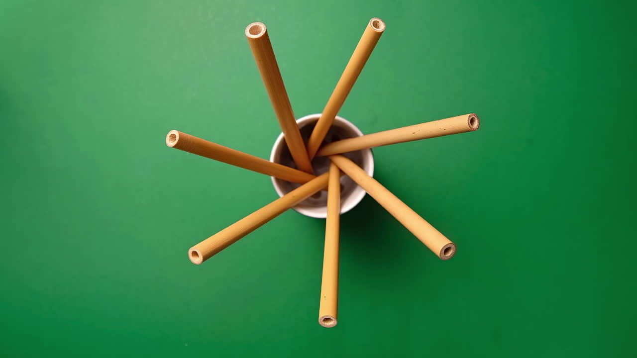 Man's hand choosing a bamboo straw from a few in a glass