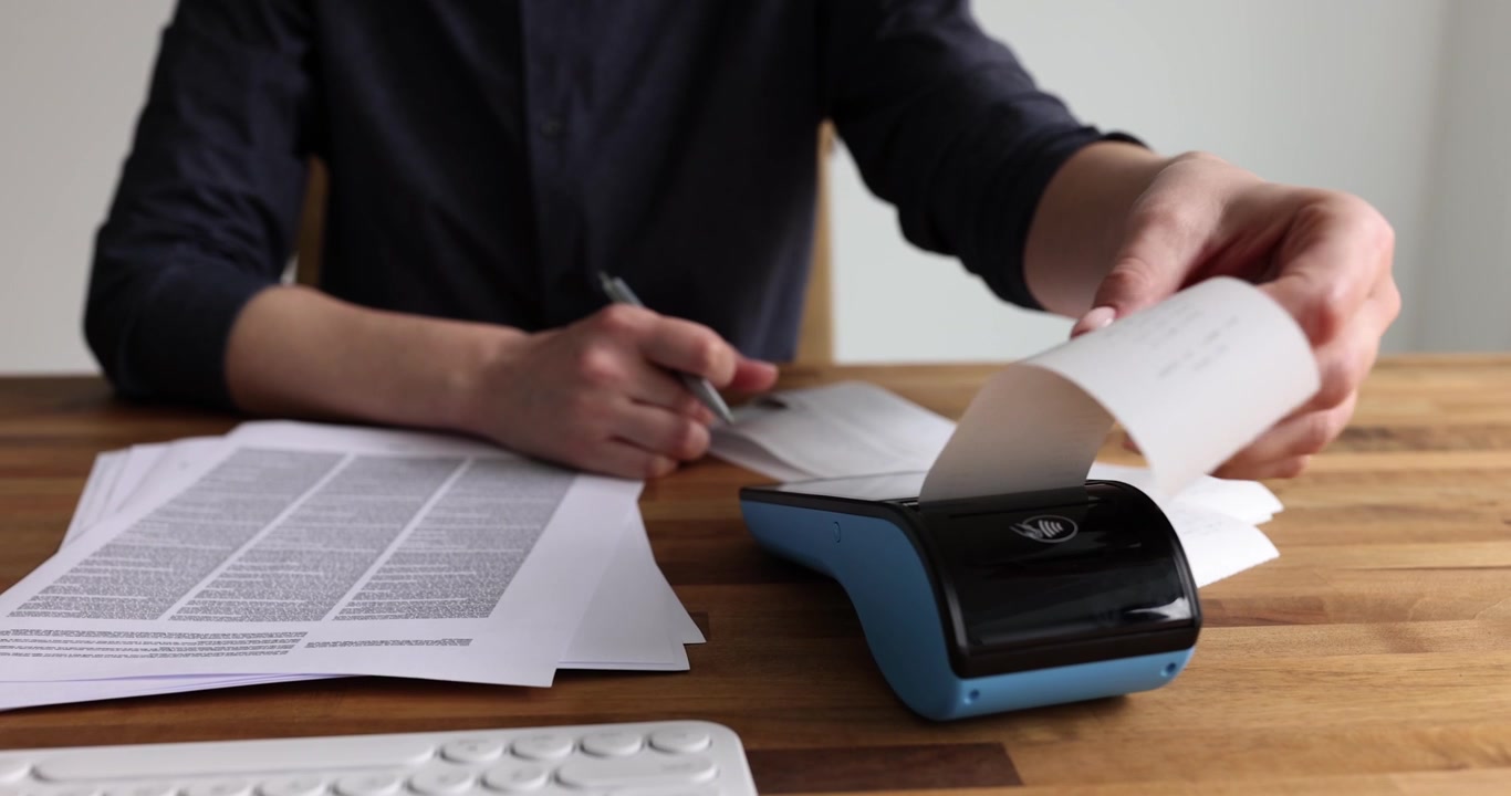 Commercialista donna lavora con terminale POS, scontrino e documenti alla scrivania