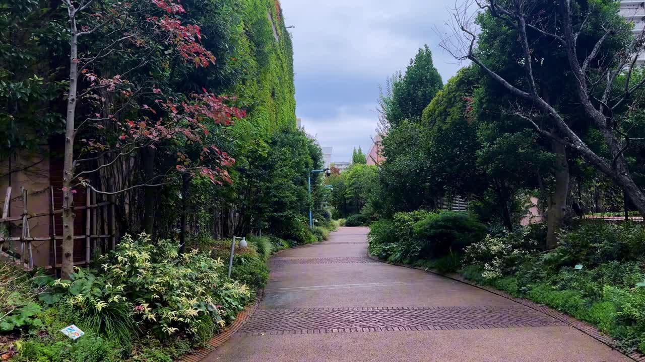 A peaceful garden path lined with lush greenery on a cloudy day