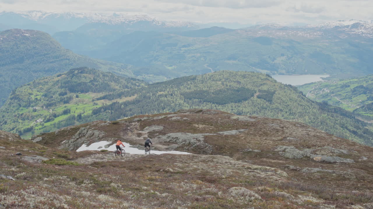 Epic mountain biking adventure above the fjords near Sogndal, Norway. Rider tackles rugged trails surrounded by dramatic cliffs, lush green hills, and stunning Nordic scenery