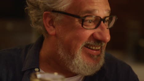 senior man making toast during dinner. mature man clicking glasses with family