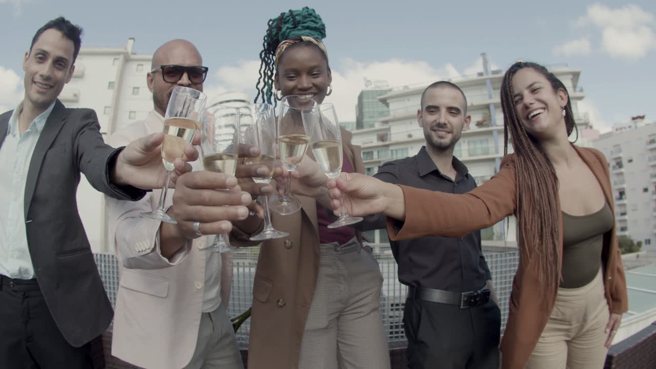 vista frontal de colegas felices tintineando vasos en la cámara