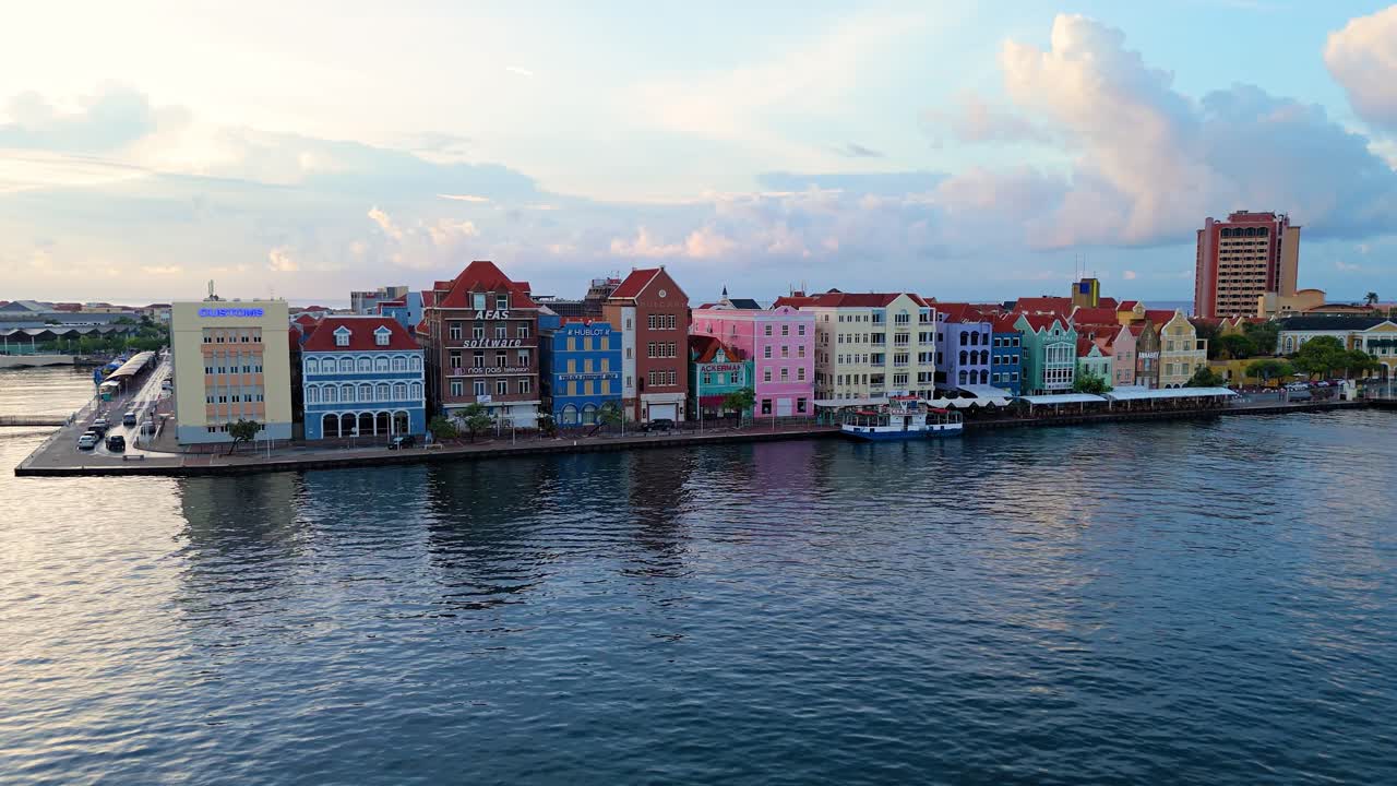 해가 뜨는 시점 에 페리 가 정박 한 물 위 에 있는 윌렘스타드 쿠라카오 의 집 들 의 부드러운 전망