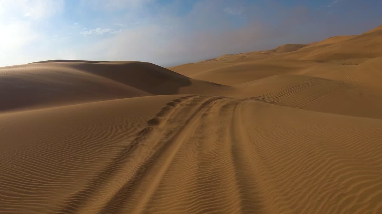 Ripresa in soggettiva dalla parte anteriore di un veicolo safari che si muove attraverso sabbia profonda e dune nel deserto del Namib in Namibia 4.