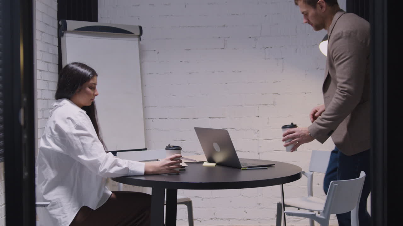 Businessman And Businesswoman With Takeaway Coffee Entering In Meeting Room