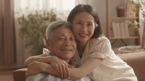 elderly asian couple embracing and smiling at home