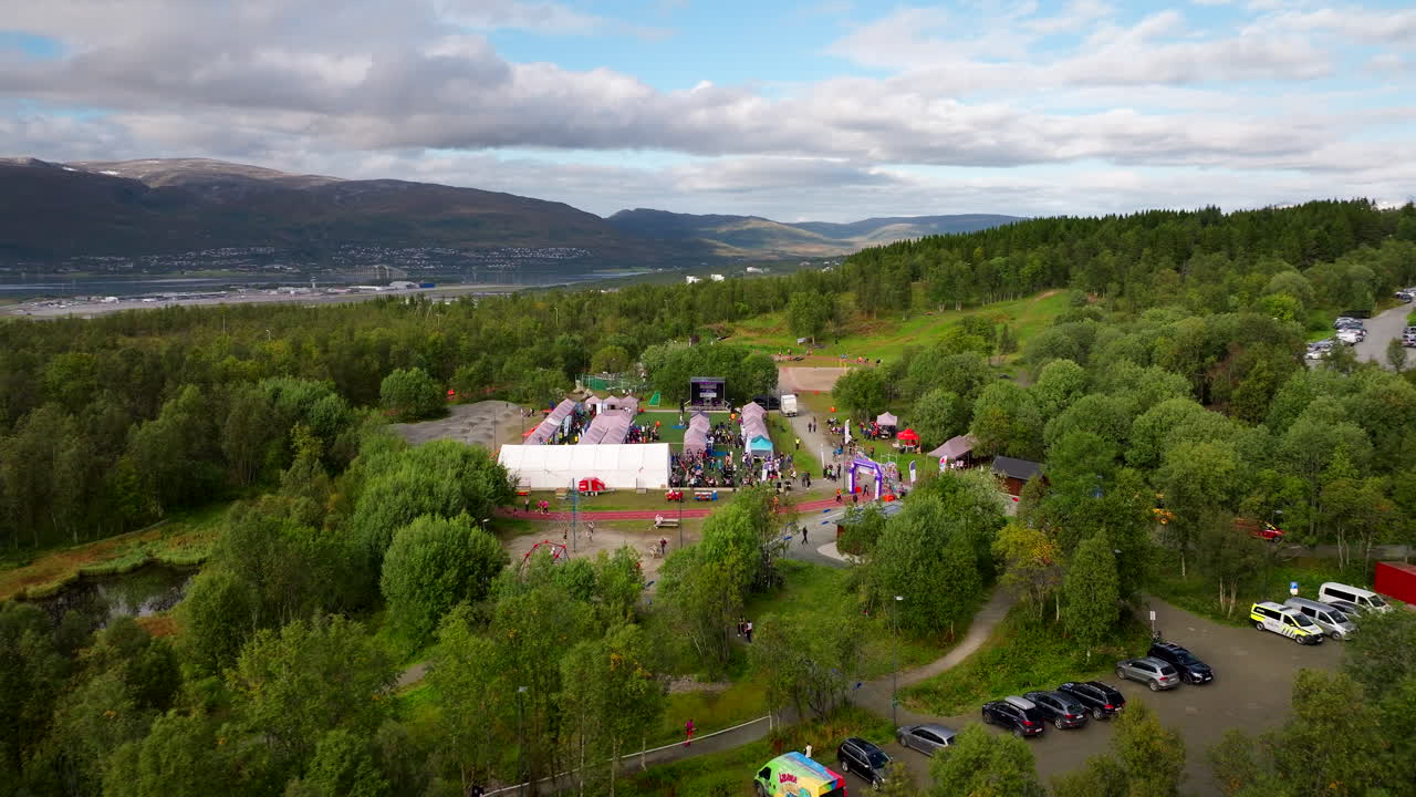 Aerial drone view of Relay for Life community fundraising event for cancer research, people gather in scenic park in Tromso, Norway