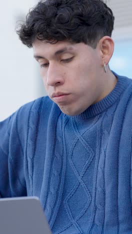 stressed young man working on laptop, feeling tired and frustrated. vertical