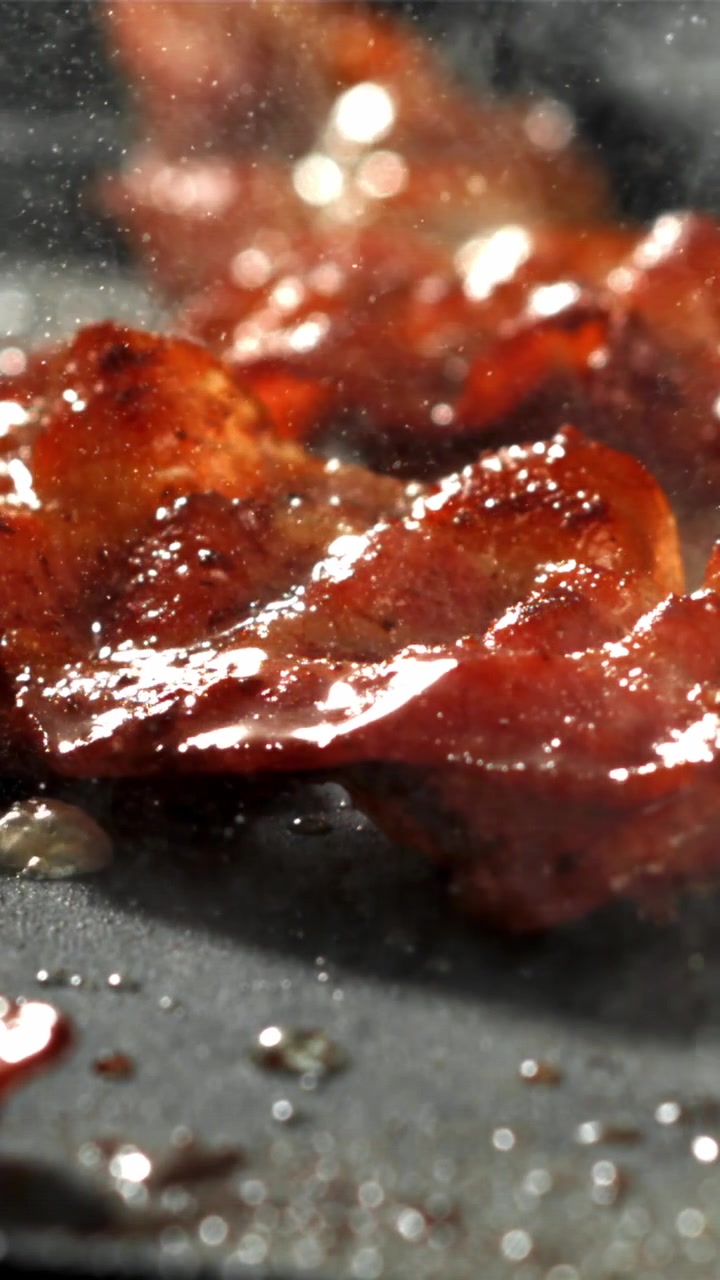 Pancetta deliziosa che cuoce e sfrigola su una padella calda