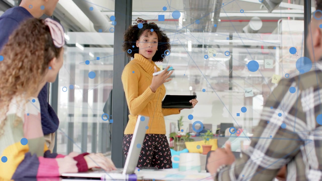 Presenter tapping tablet, gesturing and generating blue graphics, engaging colleagues in business