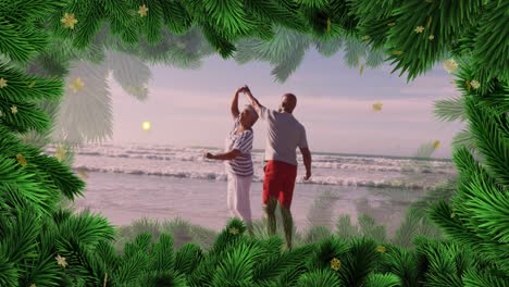 Animation-of-fir-tree-frame-over-happy-diverse-senior-couple-danging-on-beach