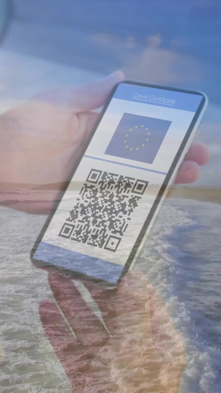 Composition of woman holding a smartphone with qr code on screen against aerial view of the beach