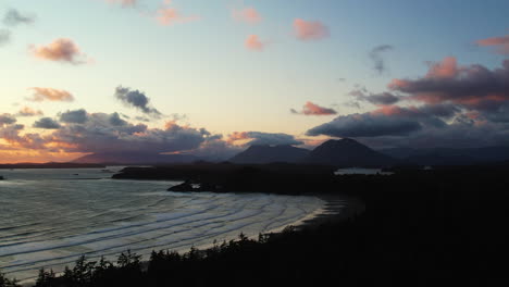 Vibrant-sunset-sky-with-waves-running-out-onto-Cox-Bay-Beach,-Tofino