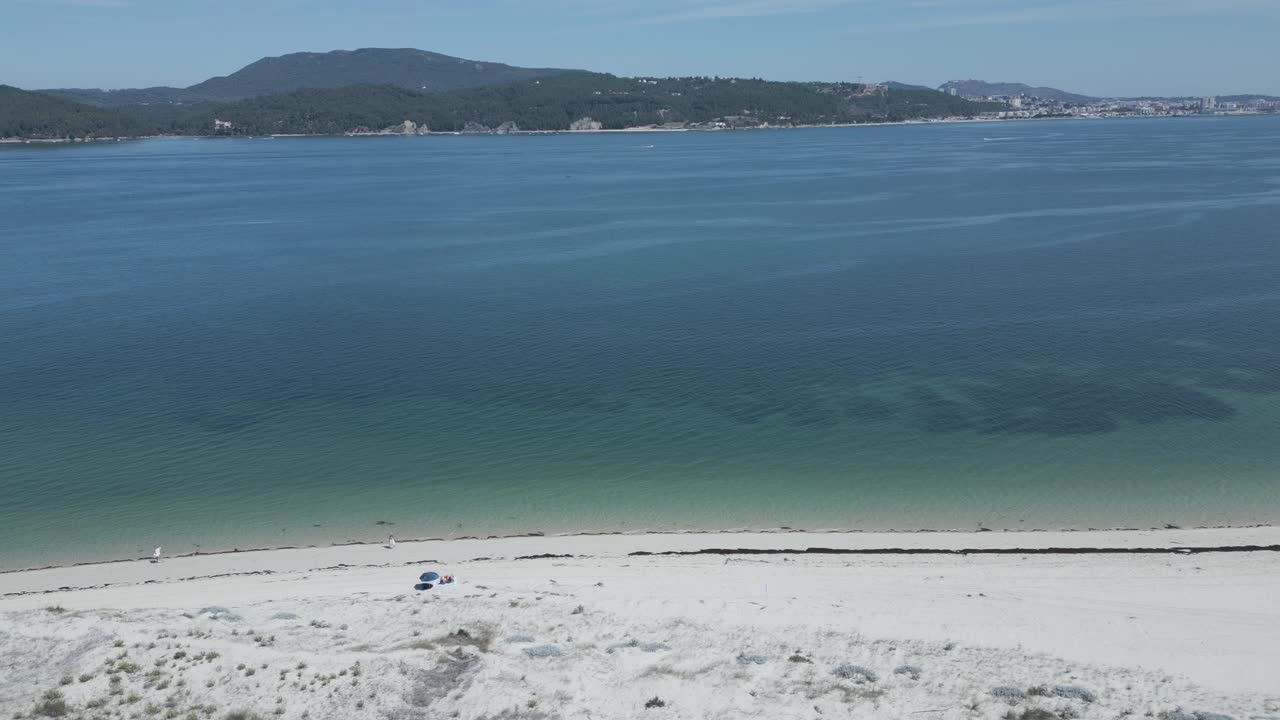 Aerial panoramic view of the Arr&aacute;bida coast, hill and beaches in Set&uacute;bal from troia island with people walking over beach, Portugal