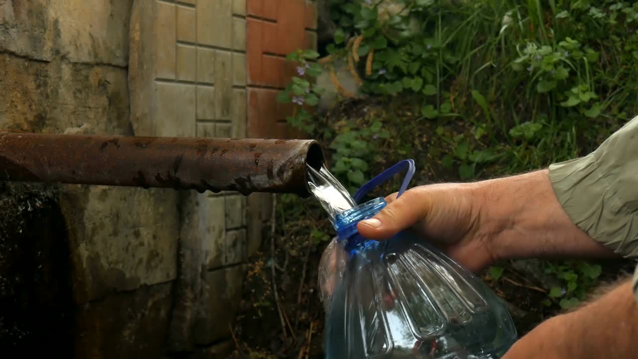 손으로 자연스러운 물을 병에 부어 넣습니다.