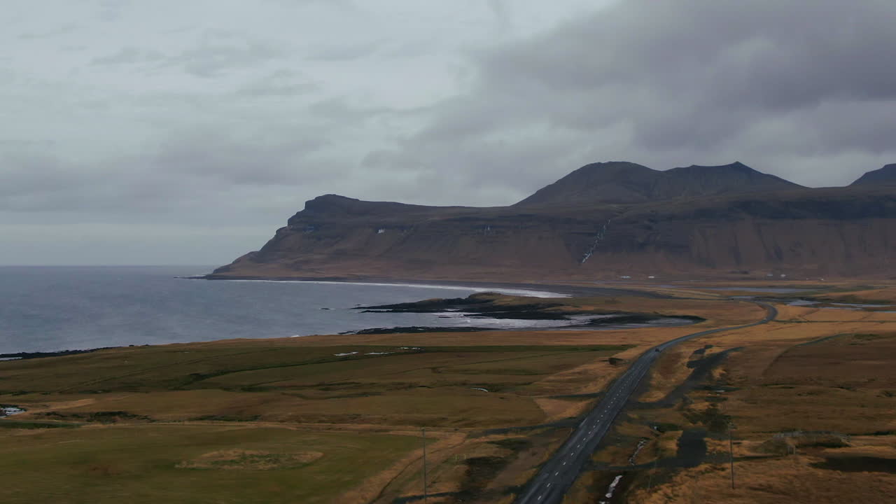 아이슬란드 의 해안 을 둘러싸고 구부러진 도로 가 있는 산 아래 해안 에 부 ⁇ 히는 물결 의 그림 같은 풍경