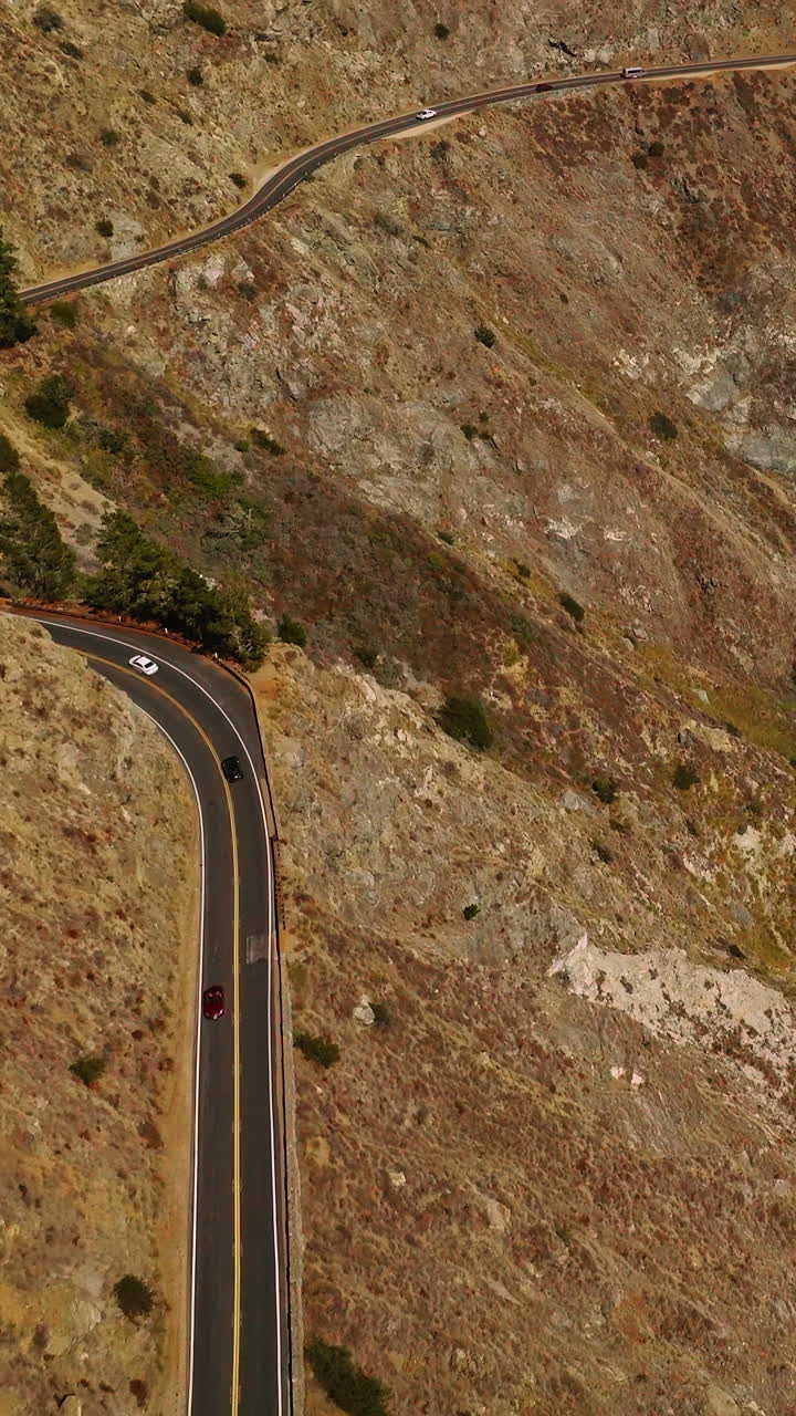 Flying over the freeway in the mountains by the Pacific Ocean. Bare rocks of Big Sur Morro Bay in California, USA. Vertical video
