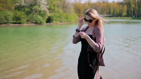 joven hermosa corrige su peinado mirándose en un espejo contra el fondo de la hermosa naturaleza