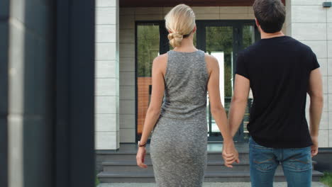 happy family going inside luxury house. rich couple holding hands.