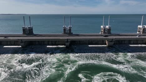 Aerial-trucking-shot-of-cars-driving-on-Zeeland-Bridge-and-dam-during-sunny-day-in-Netherlands