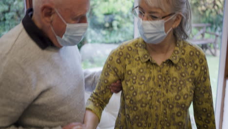 Elderly couple wearing face masks with caregiver