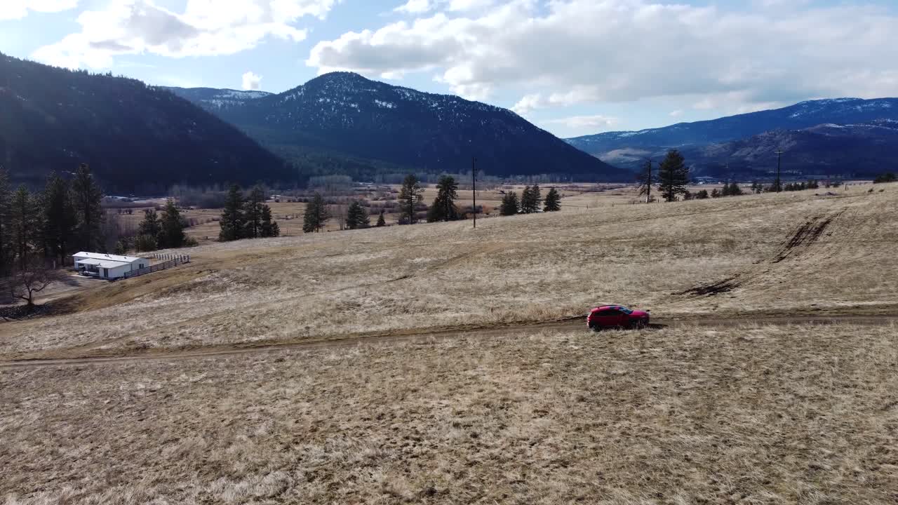 suv pasando por campos, hermosas montañas de naranja, y cielo despejado en el fondo