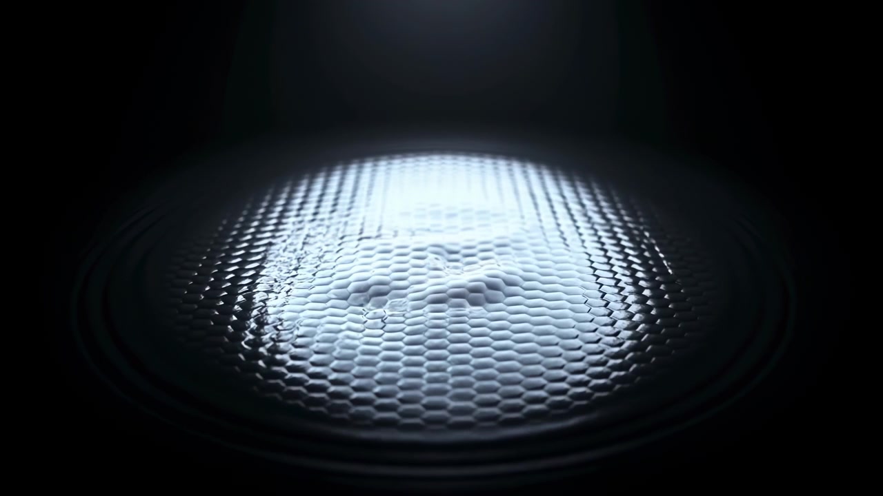 Smooth reflective surface develops changing wave patterns with bright highlights moving across curved texture, creating elegant abstract motion with dark surroundings and centered composition.