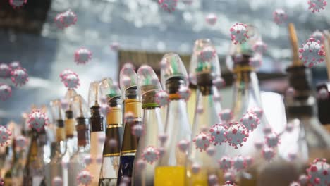 multiple covid-19 cells icons floating against colourful syrup glass bottles in background