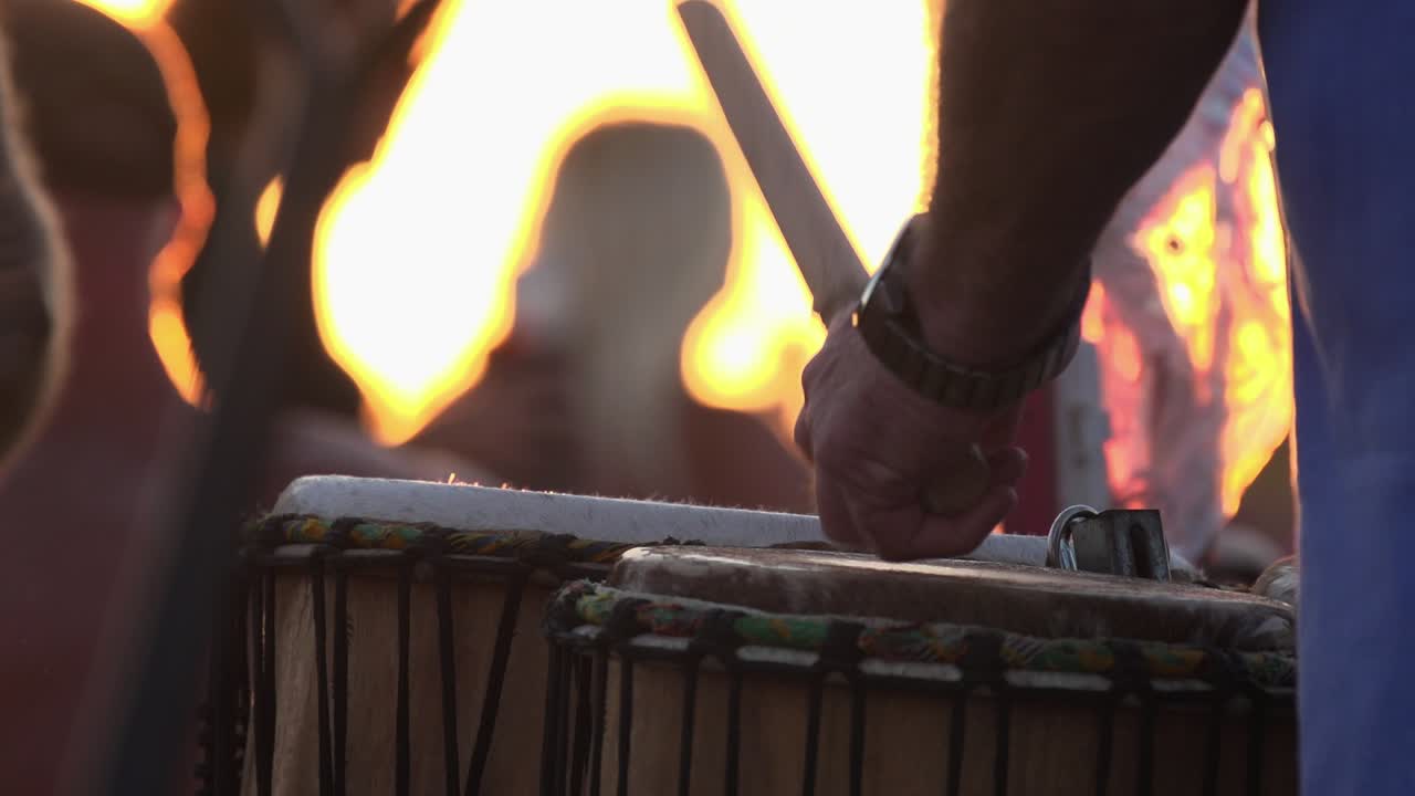cierre en cámara lenta del palo golpeando el tambor a la luz del atardecer en el círculo de tambores en la playa de siesta key