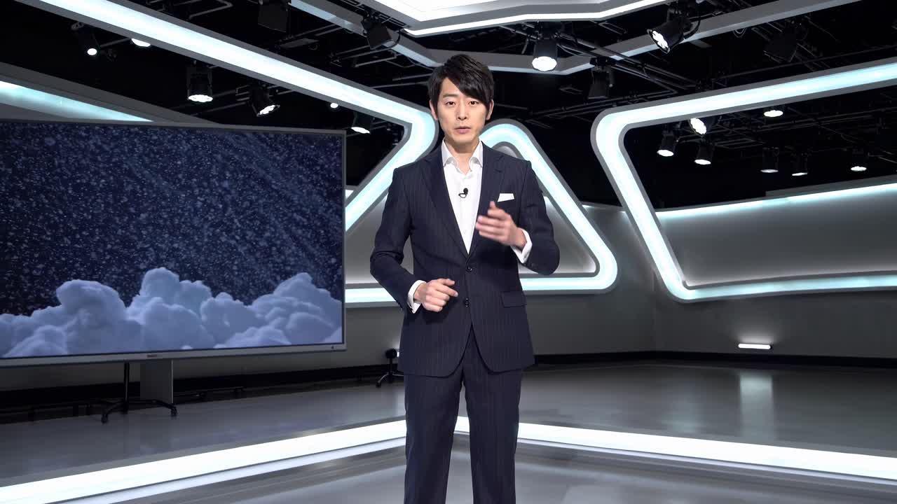 A man in a suit stands in a futuristic studio with geometric lighting