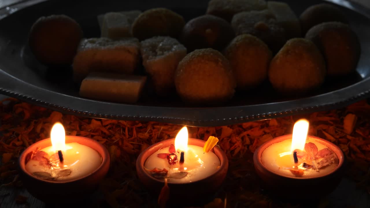 Inquadratura in picchiata da dolci indiani, dietro Diyas o lampade accese per Diwali, la 'Festa delle luci', il più importante antico festival indù celebrato che simboleggia la vittoria della luce sull'oscurità.