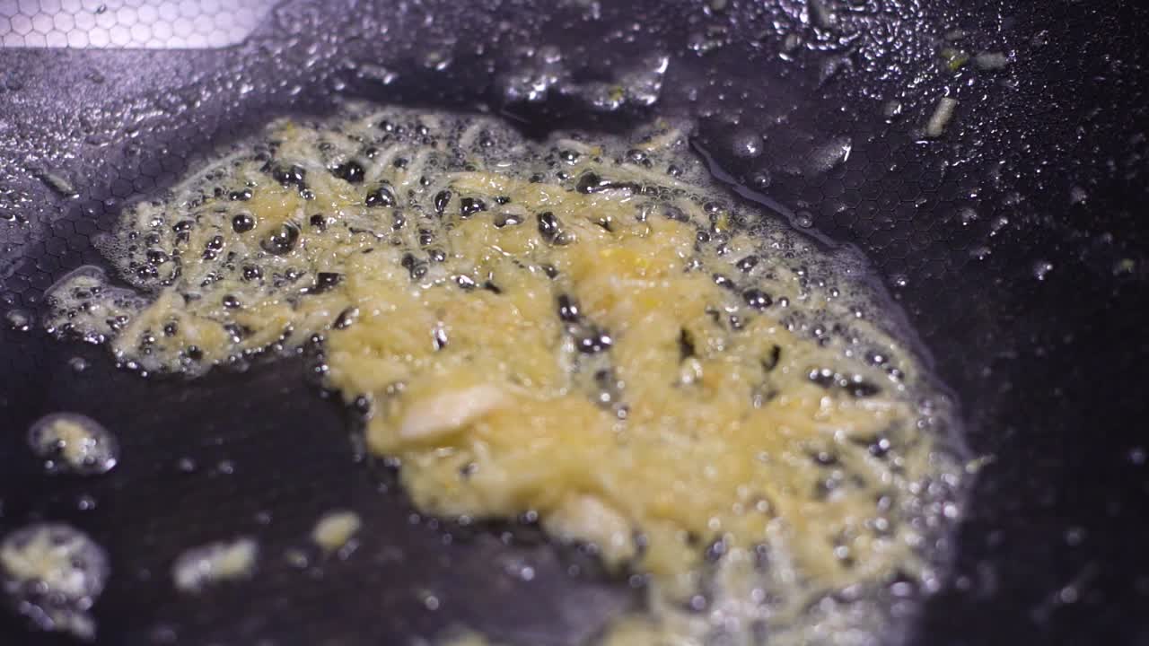 다진 마늘이 뜨거운 검은 팬에서 요리되고 있습니다.