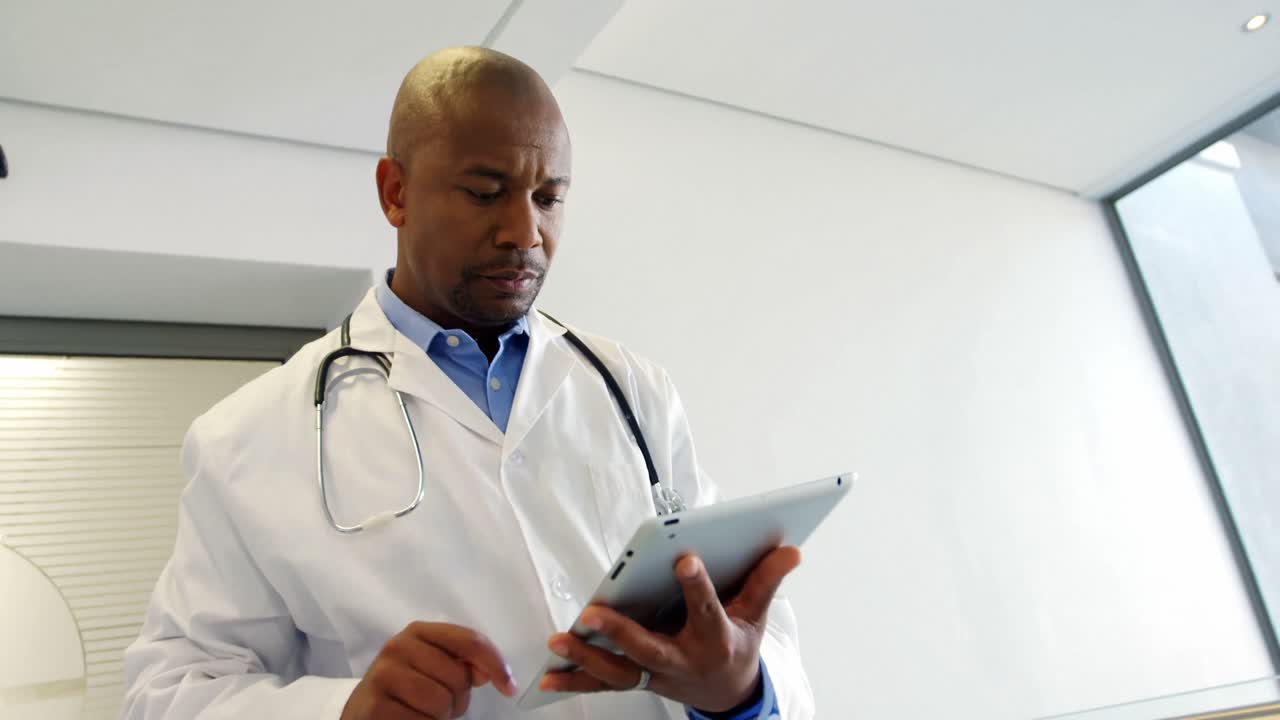 Doctor using digital tablet while walking in the corridor