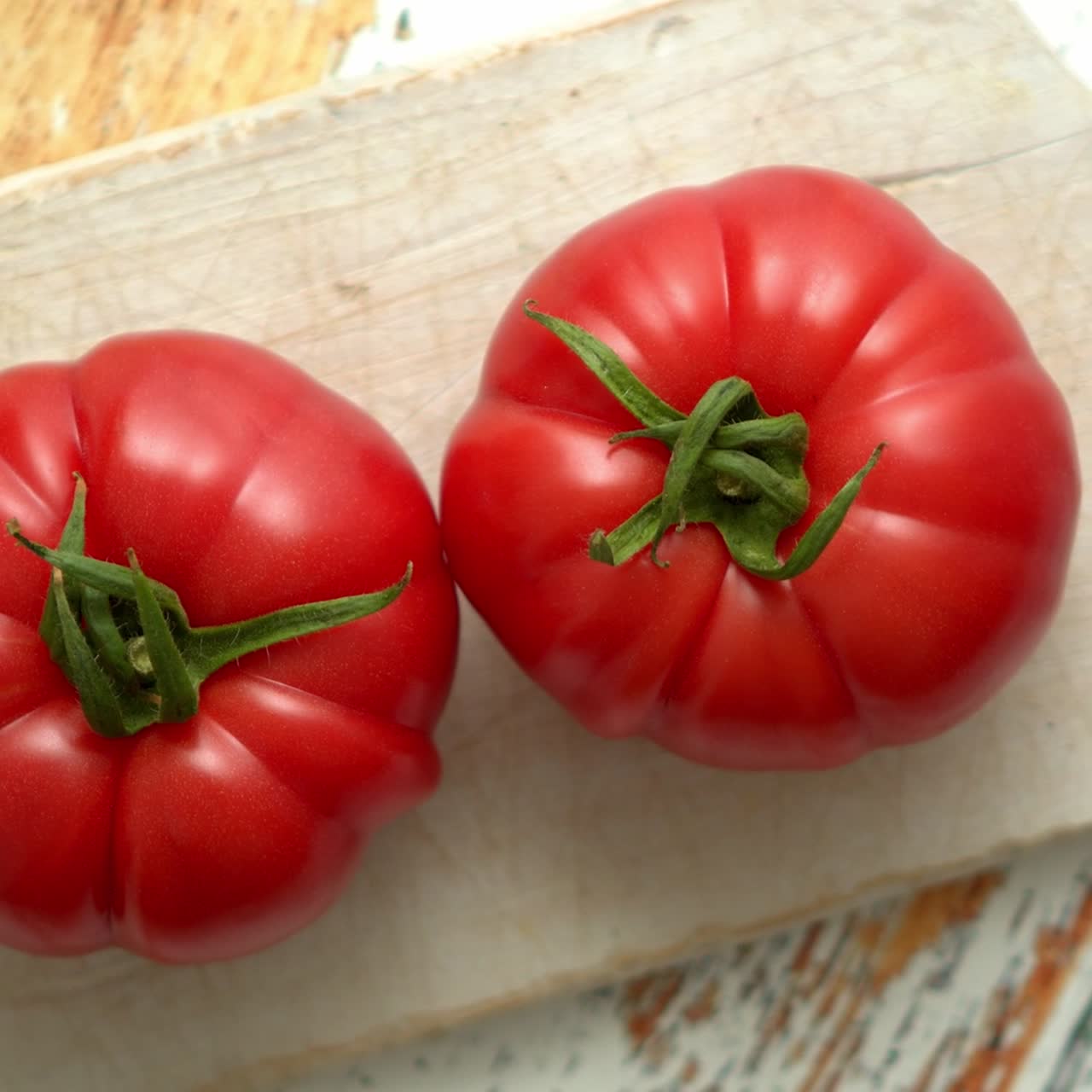 vista superior de una tabla de cortar blanca con tomates jugosos frescos sobre una mesa de madera