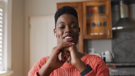 retrato de una mujer afroamericana con auriculares hablando mirando a la cámara en casa