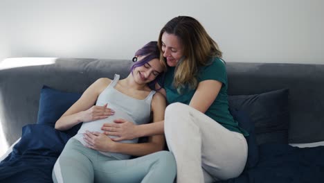 pregnant lesbian woman and her partner are happy bonding on sofa together