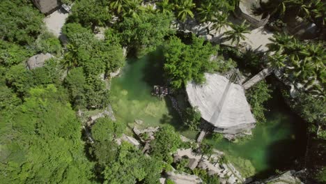 aerial view of a cenote with traditional thatched structures in tulum, mexico