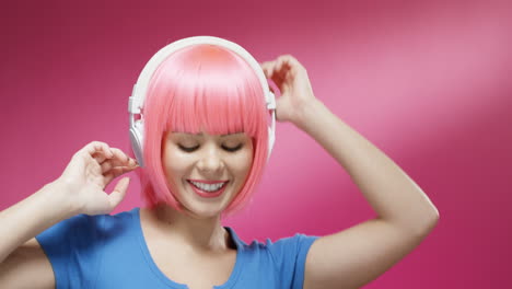 close up of attractive woman wearing a pink wig and headphones and dancing joyfully