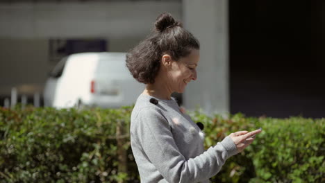 side view of middle aged woman walking on street with phone.