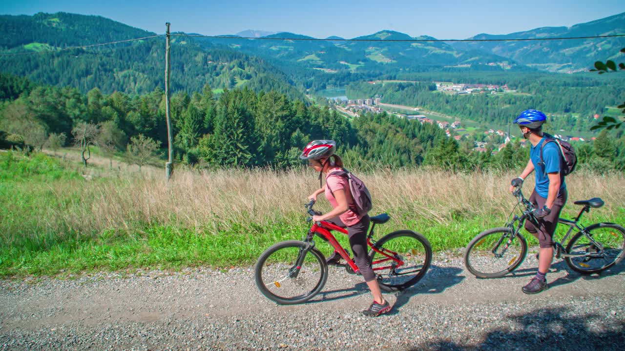 Beautiful Cyclist Couple Start Riding Bikes Overlooking Scenic Valley