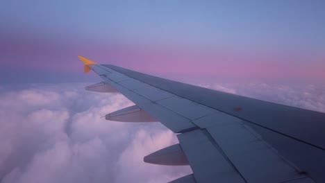 airplane wing over clouds at sunset