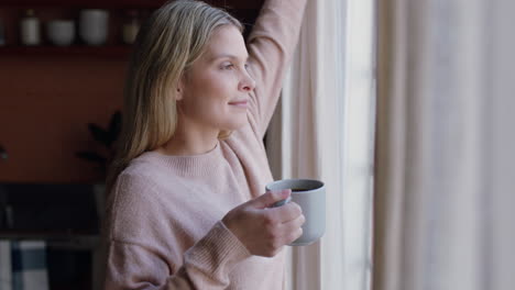 Hermosa-Joven-Abriendo-Cortinas-Mirando-Por-La-Ventana-Disfrutando-De-Un-Nuevo-Día-Sintiéndose-Descansada-Tomando-Café-En-Casa