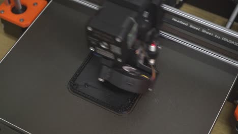 3d printer prints black square plate in the laboratory