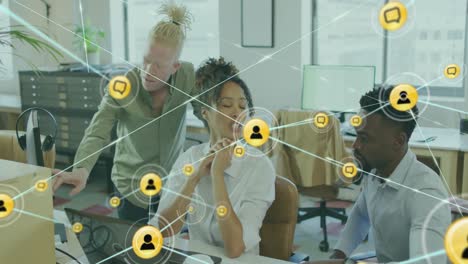 animation of icons connected with lines over diverse coworkers discussing reports on computer