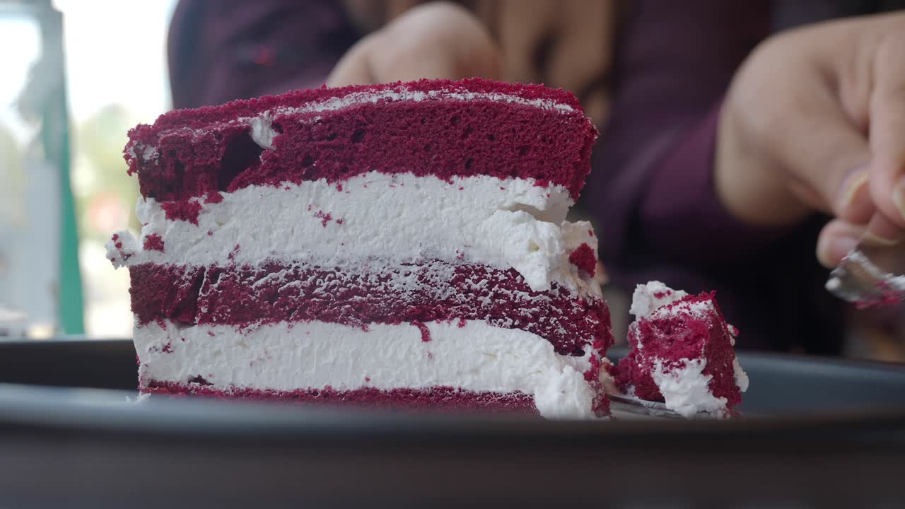Close-up of a slice of red velvet cake being eaten