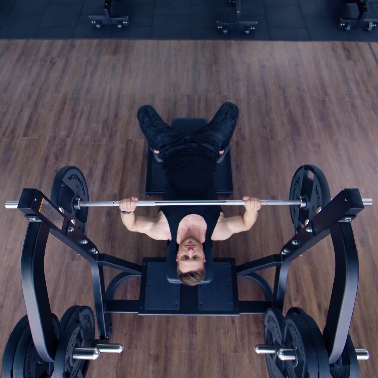 Athletic Bodybuilder Doing Barbell Exercise. Top view of professional athlete doing bench press workout with barbell