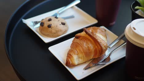 cerca de un croissant, una galleta y una taza de café en una mesa