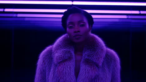 stylish woman in fur coat under purple neon lights